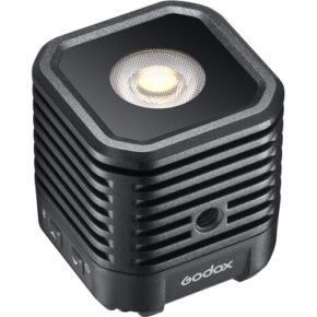 1617973841_909 Godox WL4B Waterproof LED-valaisin on kompakti, musta, kuution muotoinen LED-valaisin, jossa on kuvioitu pinta, tuuletusaukot, sivusäätöpainikkeet ja pyöreä valopaneeli yläosassa.
