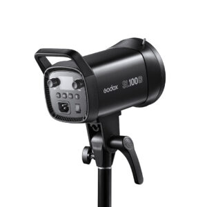 1621500353_528 Musta Godox LED SL100D Daylight -LED-valo on asennettu jalustalle, ja se on kuvattu kulmassa, jossa näkyy sen ohjauspaneeli, säätönupit ja kahva.