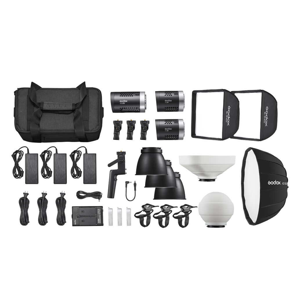 1633008497_963 Godox ML KIT1 ML60 & ML30 Trio Kit - LED-valo sisältää kolme stroboskooppivaloa, softboxit, heijastimet, jalustat, kaapelit, kaukolaukaisimen, laturin, tarvikkeet ja suuren mustan kantolaukun - kaikki siististi esillä valkoisella pohjalla.
