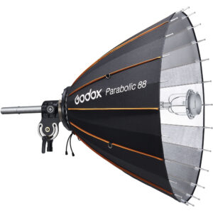 Godox Parabolic Reflector Zoom Box P88Kit -valaisimessa on musta ja hopeinen ulkokuori, jossa on oranssit korostukset, metallitangot ja musta kiinnitysteline, joka on suunniteltu studiovalaistukseen.