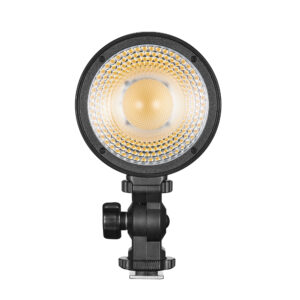 1660055369_097 Godox Litemons LED LC30Bi -pöytävideovalaisin on pyöreä, musta studiovalaisin, jossa on hunajakennomallinen diffuusori ja säädettävä kiinnike, ja se säteilee lämpimän kellertävää hehkua edestä katsottuna.