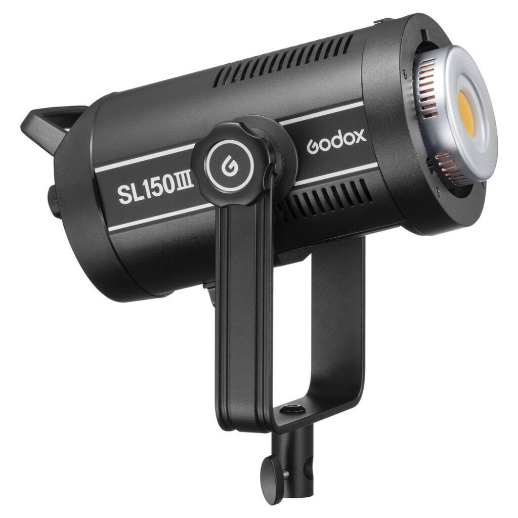 1675174001_044 Musta Godox SL150III LED-videovalaisin -LED-valo, jossa on sylinterimäinen runko, säätönuppi ja kiinnike, on kuvattu kulmassa valkoista taustaa vasten.