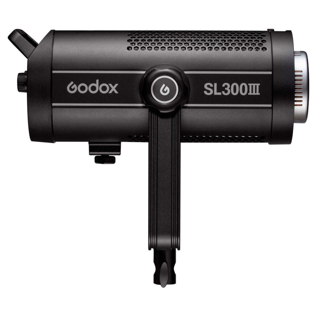 1675239117_716 Godox SL300III LED-videovalaisin -LED-valo on esitetty sivulta, ja siinä korostuvat säätönuppi, tuotemerkin logo, mallin nimi sylinterimäisessä rungossa ja pohjaan kiinnitetty kiinnike.