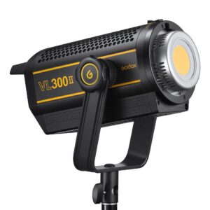 Mustakeltainen Godox VL300II LED-videovalaisin -LED-valo on asennettu jalustalle, ja sen rungossa on virtapainike ja suuret jäähdytysaukot.