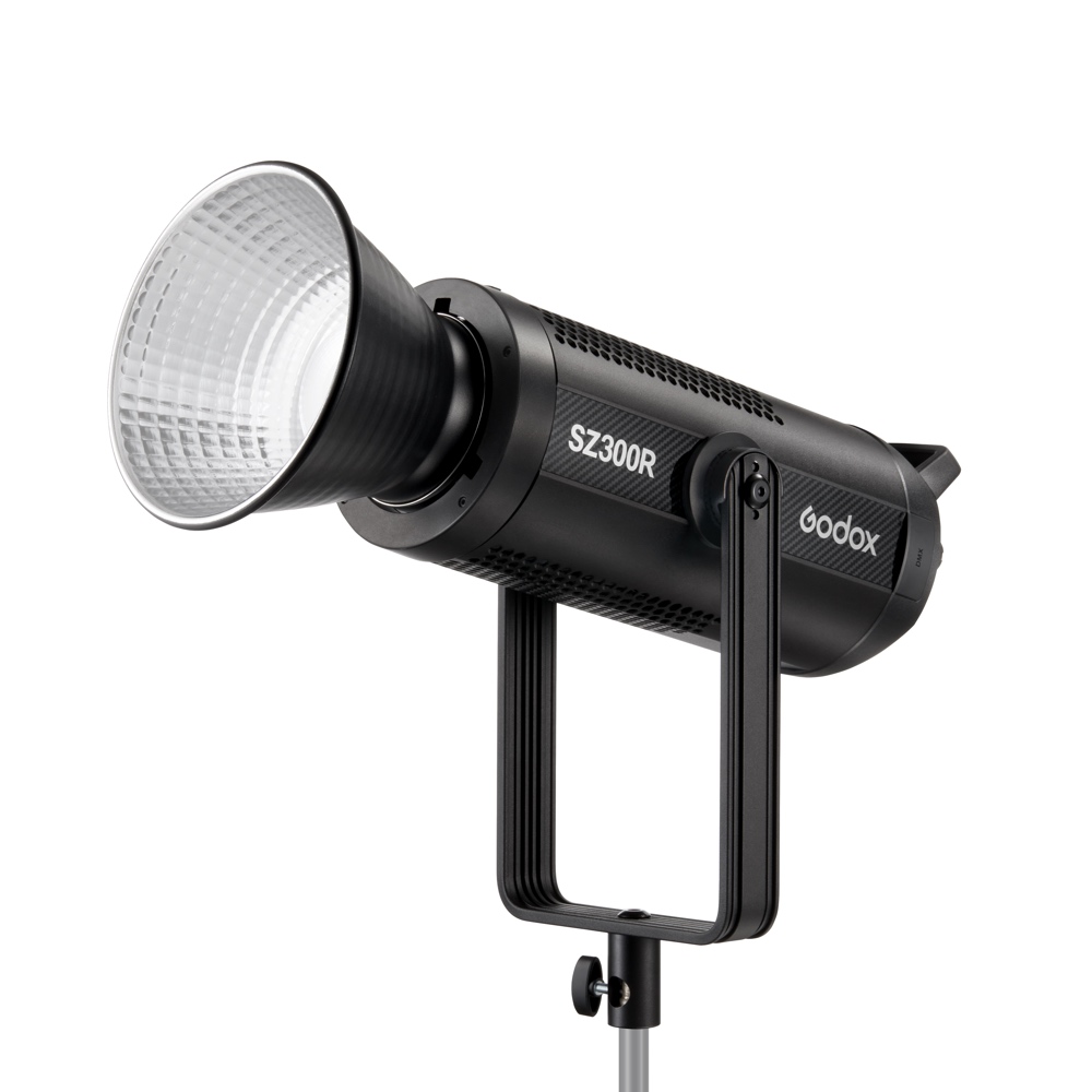 1683018529_007 Mustan värinen Godox SZ300R Zoom RGB LED Video Light -LED-valo, jossa on suuri heijastin, on asennettu metallijalustalle ja näytetään etupuolelta valkoista taustaa vasten.