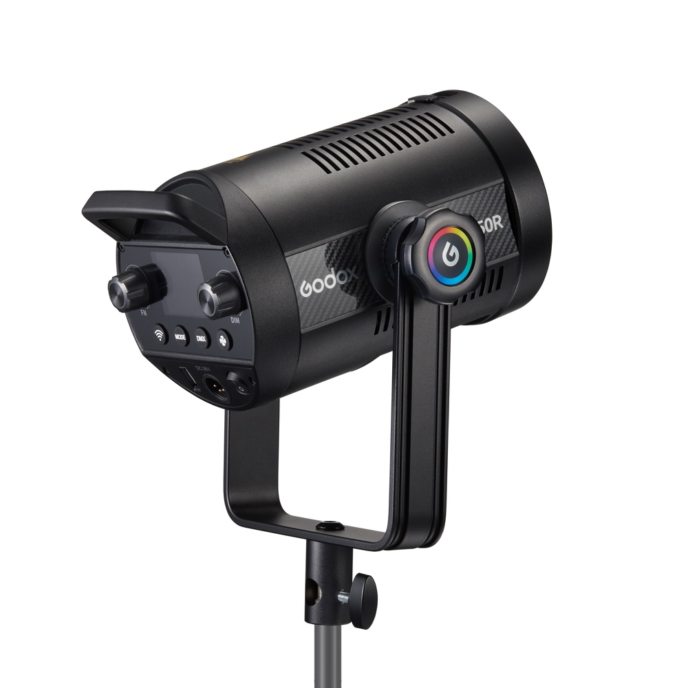 1698323707_082 Mustan värinen Godox SL150R RGB LED -videovalaisin, jossa on säätönupit ja värikäs pyöreä painike, on asennettu jalustalle ja näytetään takaa valkoista taustaa vasten.