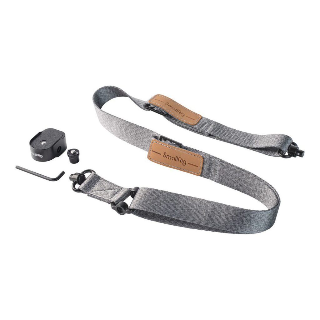 1698674742_247 SmallRig 4118B Painoa vähentävä olkahihna DJI RS 3/RS 3 Pro/RS 2/RSC 2:lle on kuvassa harmaa kangashihna ruskeilla nahka-aksenteilla, musta kiinnityslevy, ruuvi, kuusiokoloavain ja pieni rengas valkoisella pohjalla.