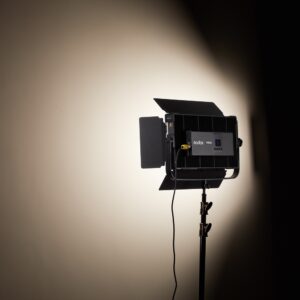 1704806426_926 Kolmijalkaiseen jalustaan asennettu Godox P200BI Studio LED-valopaneeli on kytketty päälle, ja se heijastaa kirkkaan, fokusoidun valonsäteen tavalliselle beigelle seinälle luoden pehmeän varjostuksen valaistun alueen ympärille.