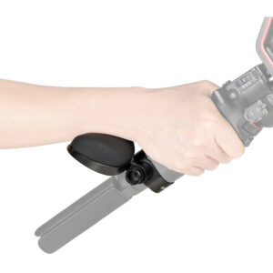 1706276905_785 Käsi tarttuu kameraan, johon on kiinnitetty jalusta, käyttäen SmallRig 4248 Wrist Support for DJI RS Series -rannetukea. Tuki on pieni ja musta, ja se sijoitetaan ranteen alle. Kamera ja jalusta ovat osittain näkyvissä ja puoliksi läpinäkyviä.