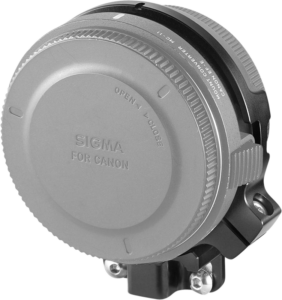 Sigma-objektiivin kiinnityssovitin Canon-kameroille, kuvassa suojakorkit päällä, hopeanvärinen ja musta runko, jossa on näkyvä kuvioitu kahva ja lukitusmekanismi.