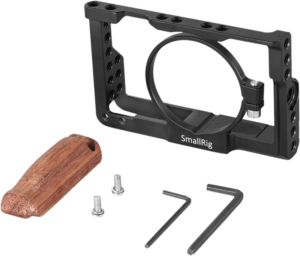 800q-02_113186 SmallRig 2225 Cage Kit Sony RX100 VI:lle sisältää mustan metallikehyksen, ruskean puukahvan, kaksi ruuvia ja kaksi kuusiokoloavainta, jotka kaikki näkyvät valkoisella pohjalla.