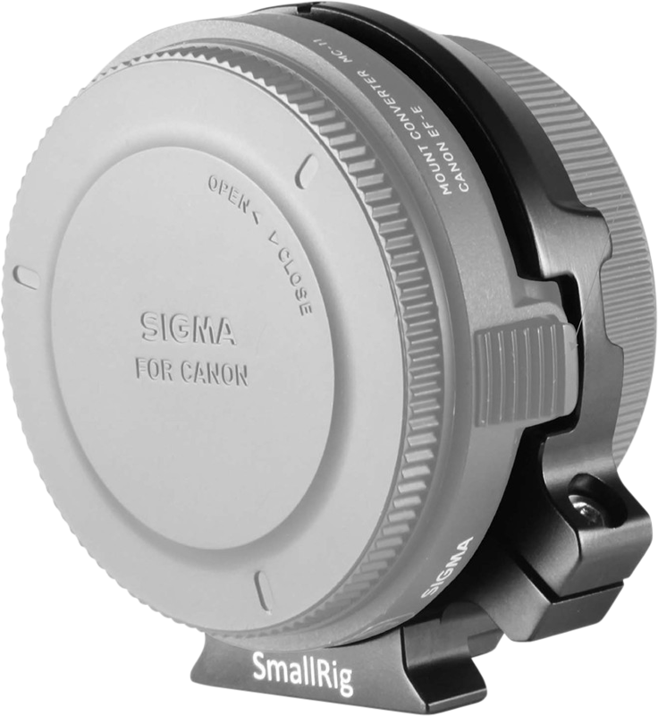 Lähikuva Sigma-objektiivin Canon-kameroille tarkoitetusta objektiivin kiinnitysmuuntimesta, joka on kiinnitetty metalliseen SmallRig-tukikiinnikkeeseen, ja jossa näkyvät aukeamis- ja sulkeutumisilmaisimet sekä tuotemerkki.