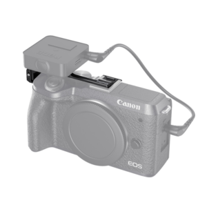 SmallRig 2627 Vlogging Cold Shoe Relocating Plate -levy on kiinnitetty harmaasävyisenä esitettyyn Canon EOS M6 MkII -peilittömään kameraan, jolloin pieni suorakulmainen langaton mikrofonivastaanotin voidaan liittää kylmäkengän ja ääniportin kautta.