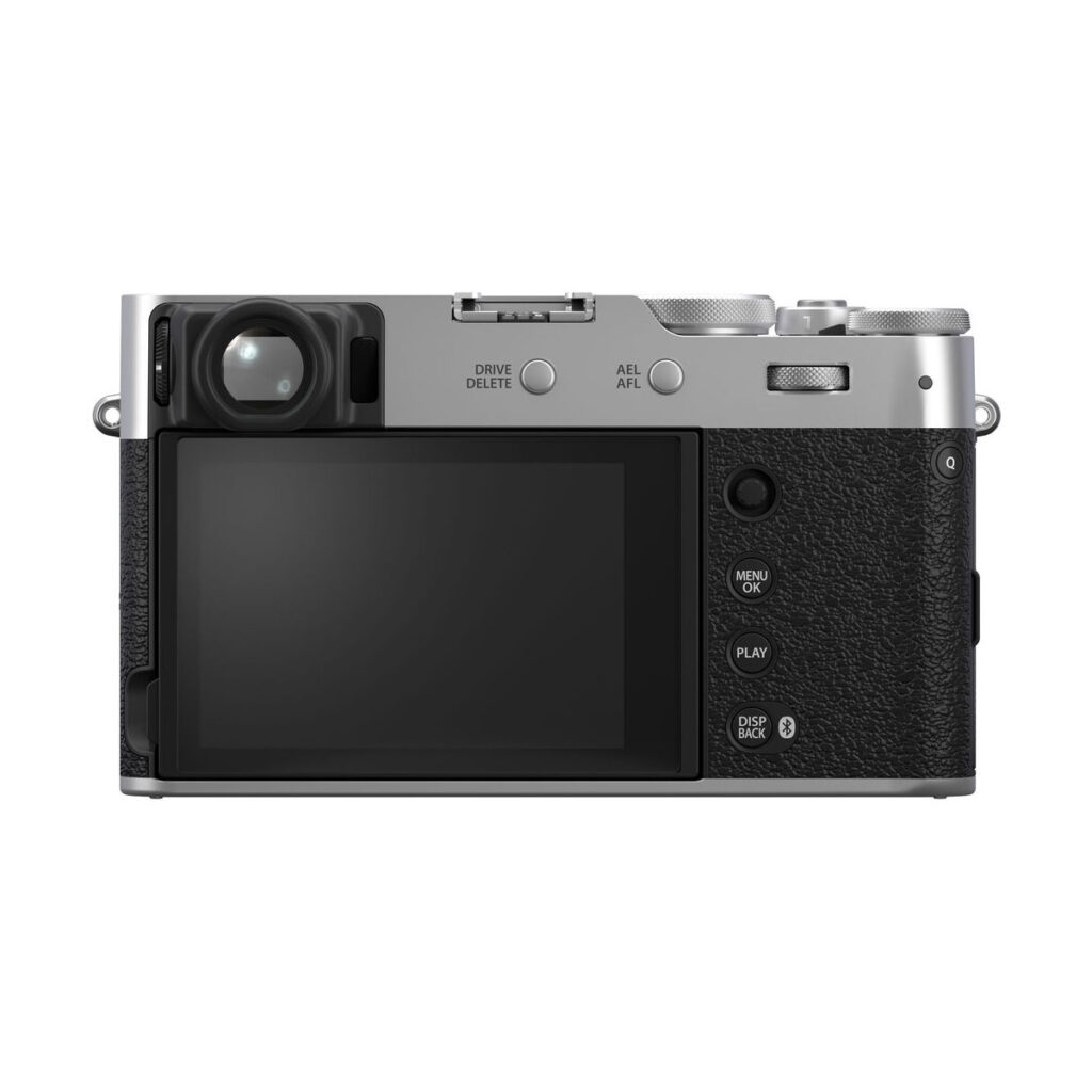 fuji_x100vi_hopea_06 Fujifilm X100VI -kompaktikameran takanäkymä, hopea, jossa näkyy suuri LCD-näyttö, erilaisia säätöpainikkeita ja -valitsimia sekä kuvioitu musta-hopea runko valkoista taustaa vasten kuvattuna.