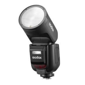 godox_v1_pro_canon_06 Musta Godox V1 Pro -salama Canon-kameroille, jossa on pyöreä pää, on kuvassa ylöspäin suunnattuna. Godoxin logo näkyy rungossa ja päässä, ja alareunassa näkyy kiinnityskannatin.