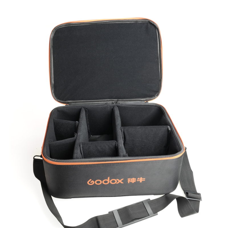 1489431433_483 Godox AD600 Bowens TTL Complete KIT sisältää mustan kantolaukun, jossa on oranssi reunus, säädettävät pehmustetut väliseinät, useita lokeroita ja olkahihna laitteiden järjestettyä säilytystä varten.