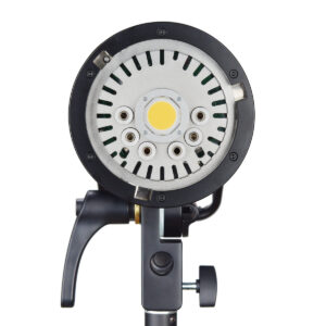 1529661017_941 Lähikuva Godox H600P - AD600PRO ulkoisesta salamapäästä 600ws Bowens, jossa näkyy sen pyöreä metallipinta, jossa on ruuvinreiät ja keltainen keskivalopaneeli, asennettuna mustaan säädettävään jalustaan valkoista taustaa vasten.