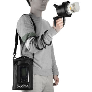 1560261309_067 The person is wearing a grey sweater and light-coloured trousers, and is holding a hand-held salamander connected by a coiled cable to a Godox AD600Pro power supply hanging over his shoulder in a black Godox PB-600P Portable Bag.