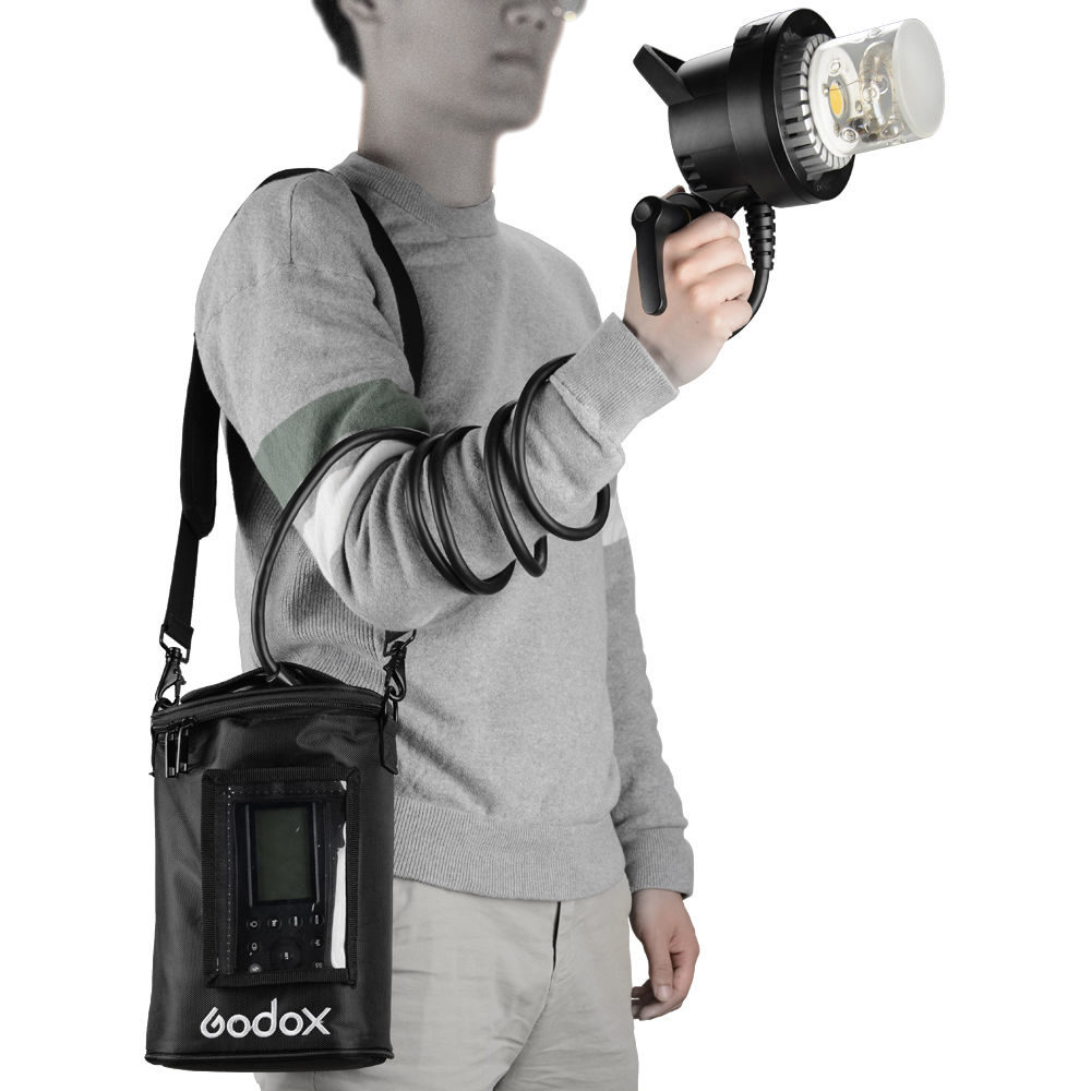 1560261309_067 The person is wearing a grey sweater and light-coloured trousers, and is holding a hand-held salamander connected by a coiled cable to a Godox AD600Pro power supply hanging over his shoulder in a black Godox PB-600P Portable Bag.