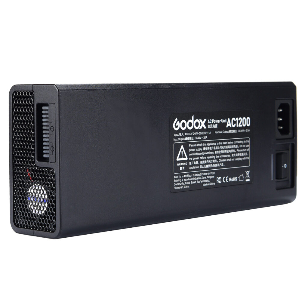 1586157220_317 Suorakulmainen musta Godox AC-adapteri AD1200Pro, jossa on tuuletusaukko, virtakytkin ja merkintäpaneeli, jossa on tekniset tiedot ja sertifiointilogot toisella puolella.
