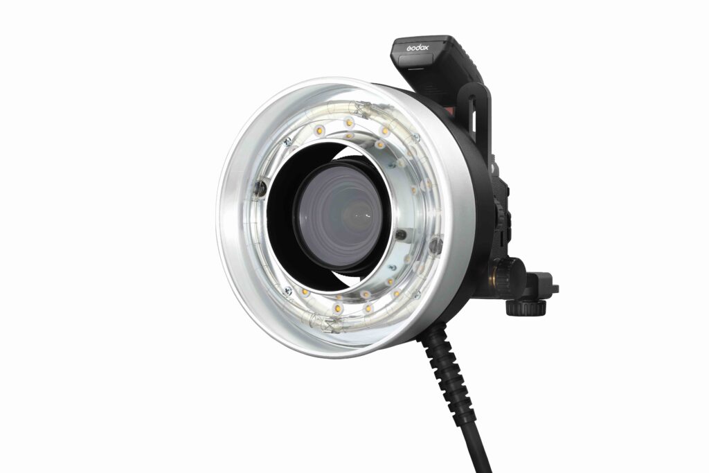 Lähikuva Godox R1200 Ring Flash Head -salamapäästä AD1200Pro:lle, jossa on pyöreä LED-rengas linssin ympärillä ja joka on liitetty kelattuun virtajohtoon.