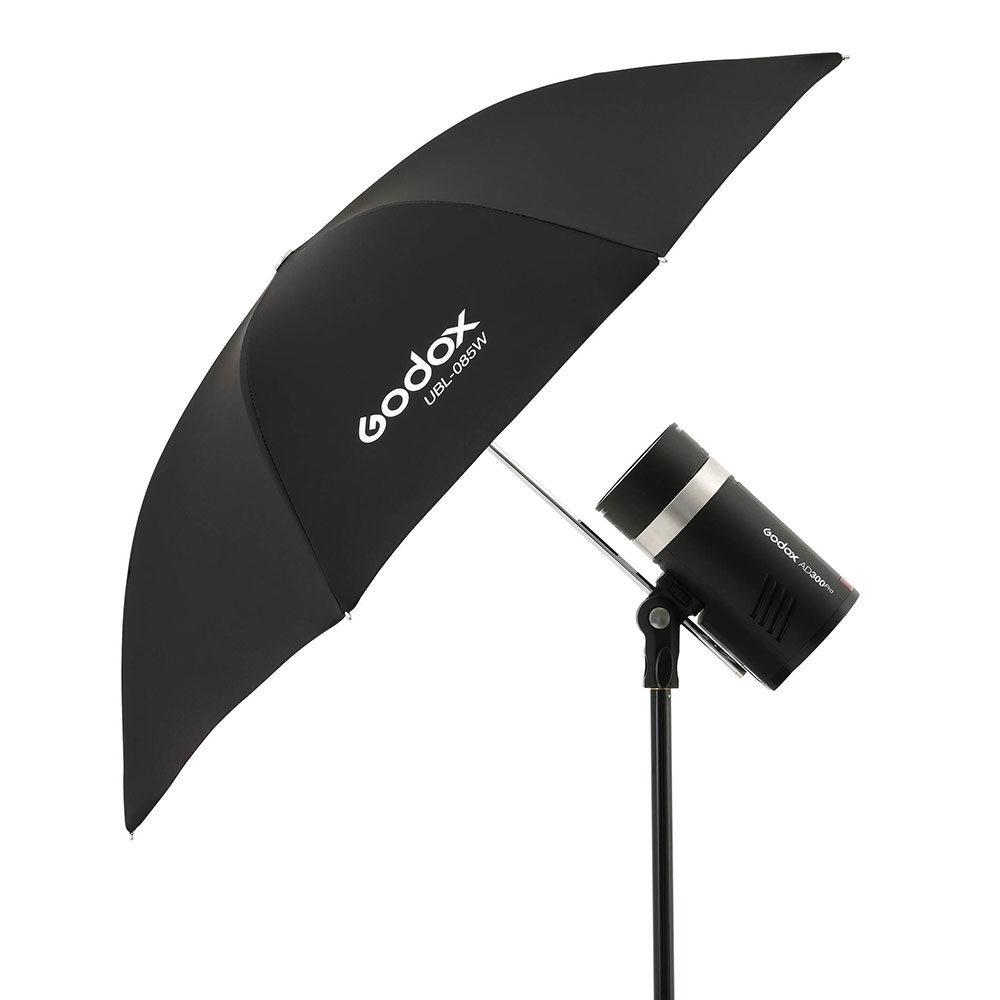 1605010704_171 Godoxin valkoinen sateenvarjo 85cm AD300Pro:lle ja Godoxin studiovalo mustalla jalustalla, kulma valkoista taustaa vasten.