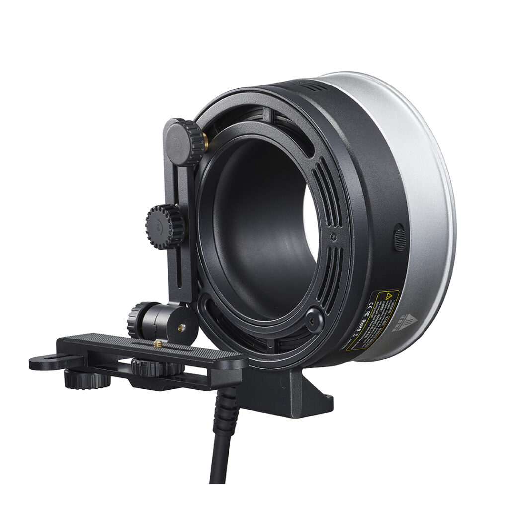 1620046434_666 Godox FLB-90 Quick Rotating Camera Bracket Kit for R1200 -valokuvakameran kiinnityssarjassa on säätöpainikkeet, suuri pyöreä aukko ja liitetty virtajohto, joka on suunniteltu valokuvaus- tai videokuvauslaitteille, kuvassa tavallisella valkoisella pohjalla.