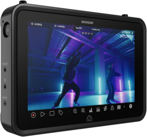 ATOMOS SHOGUN 7-tuumaisen HDR Monitor-Recorder 6K RAW -näytön lähikuvassa näkyy kaksi ihmistä tanssimassa värikkäässä, neonvalaistussa teollisuusympäristössä, ja kameran asetukset ja ohjauskuvakkeet näkyvät sen näytöllä.