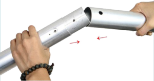 800q-02_122084 Two hands connect two NANLITE Background Tube 3 metre tubes; one tube is inserted into the other, and the red arrows highlight the point of connection.
