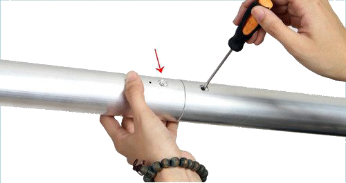 800q-03_122084 A person uses a screwdriver to tighten a screw that connects two NANLITE Background Tube 3-meter tubes; one hand holds the tube while the other turns the screwdriver, the red arrow points to the screw.