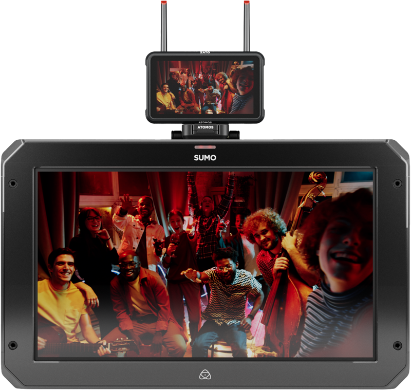800q-03_125019 Pieni ATOMOS Z-Mount -monitori on isomman näytön päällä, ja molemmissa näkyy iloinen joukko ihmisiä poseeraamassa ja hymyilemässä lämpimästi valaistussa huoneessa, ja joillakin on kädessään soittimia.