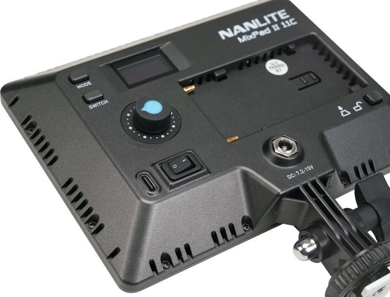 800q-04_116536 Lähikuva NANLITE MixPad 11C II RGBWW LED-paneelin takapaneelista, jossa näkyvät ohjauspainikkeet, moodivalitsin, kytkin, digitaalinäyttö ja paristolokero. Laite on osittain asennettu tukivarteen.