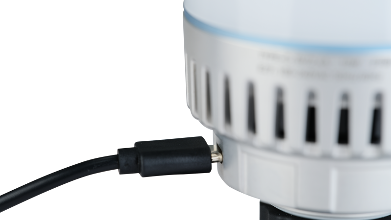 800q-04_118876 Lähikuva NANLITE USB-C to DMX Cable Splitter -kaapelinjakajasta, joka on kytketty pyöreään, valkoiseen laitteeseen, jossa on sivussa tuuletusrakoja tavallista taustaa vasten.