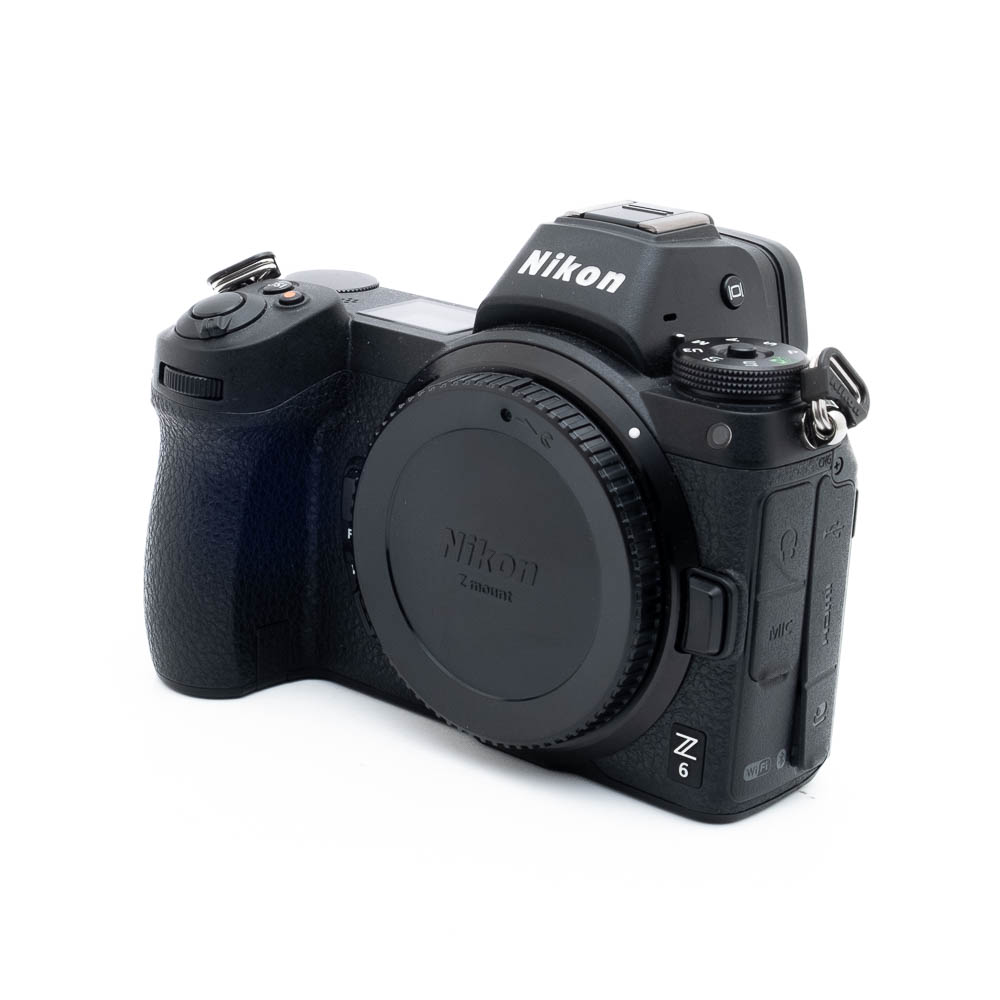 Nikon Z6 3260-5 Käytetty Nikon Z6 (SC 3500) -kamerarunko, musta, kuvattu edestä vasemmalta ilman objektiivia valkoista taustaa vasten.