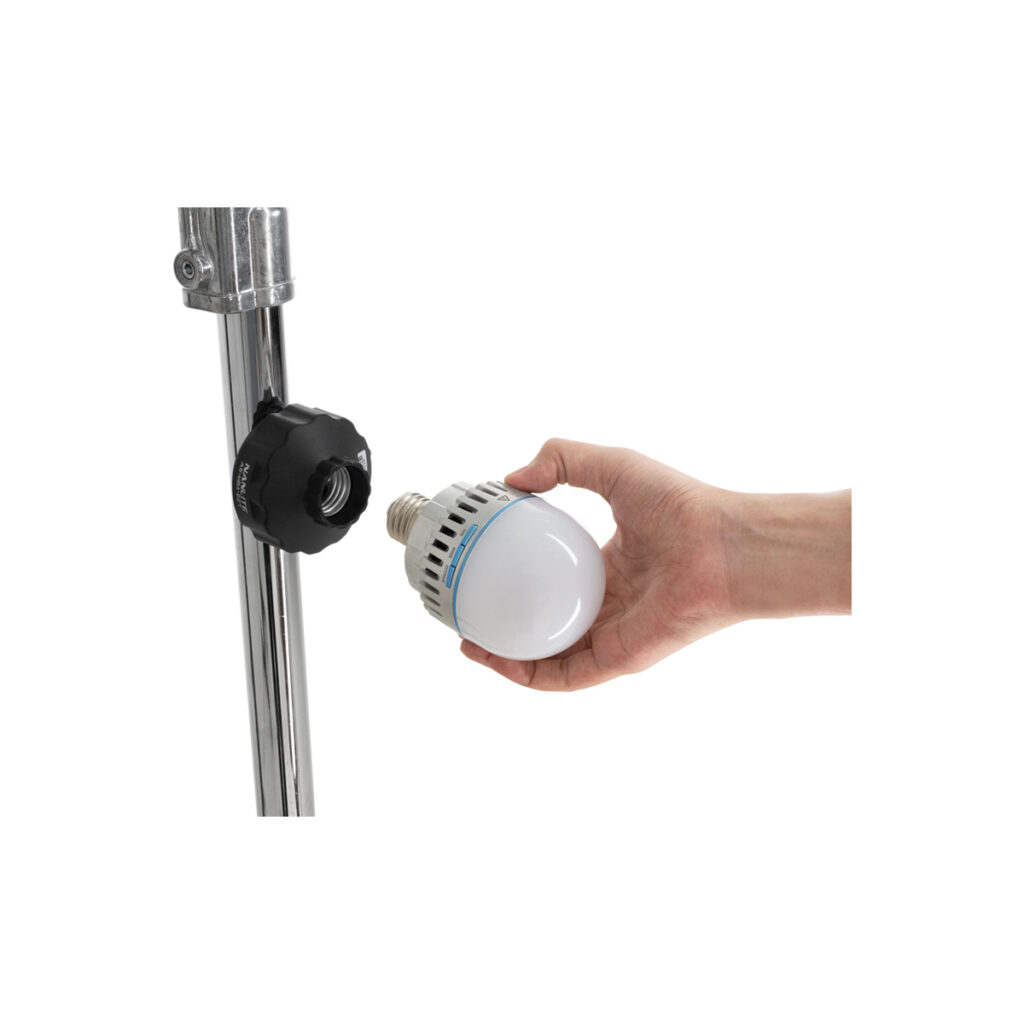 nane27mag2 Käsi pitää valkoista LED-lamppua lähellä metallista pylvästä, jossa on musta NANLITE E27 -magneettisovitin, ja näyttää asentavan tai irrottavan lamppua.