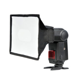 Godox Portable Softbox for Speedlite 15x20cm on kiinnitetty kameran salamaan, joka seisoo pienellä mustalla jalustalla valkoista taustaa vasten.