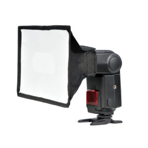 1360160301_334 Godox Portable Softbox for Speedlite 15x20cm on kiinnitetty kameran salamaan, joka seisoo pienellä mustalla jalustalla valkoista taustaa vasten.