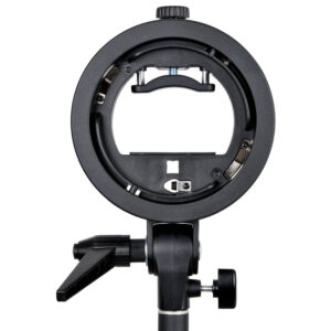 1448260728_587 Lähikuva Godoxin S-kiinnikkeellä varustetusta Elinchrom Rotolux -valaisimesta ja 60x60 cm:n Softboxista, joka on asennettu valaisinjalustalle ja kuvattu valkoista taustaa vasten.