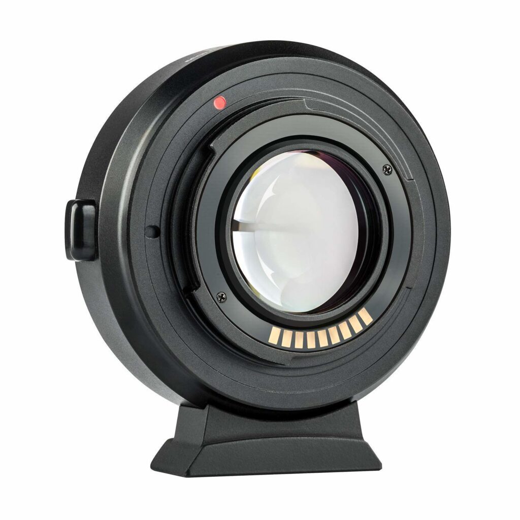1547044526_175 Lähikuva mustasta Viltrox EF-FX2 Autofocus Adapter 0,71x -objektiivista, jossa on lasielementti, elektroniset koskettimet ja punainen kohdistuspiste, joka on pystyssä pienellä alustalla valkoista taustaa vasten.