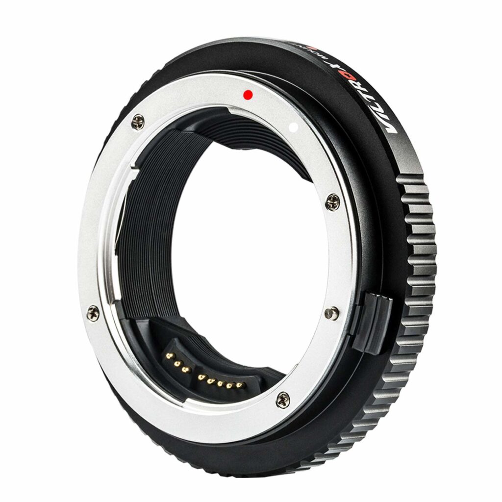 1547044581_872 Lähikuva Viltrox EF-GFX II Autofocus Adapterista, mustasta ja hopeisesta kameran objektiivisovitinrenkaasta, jossa on elektroniset koskettimet ja punainen kohdistuspiste, eristettynä valkoisella taustalla.