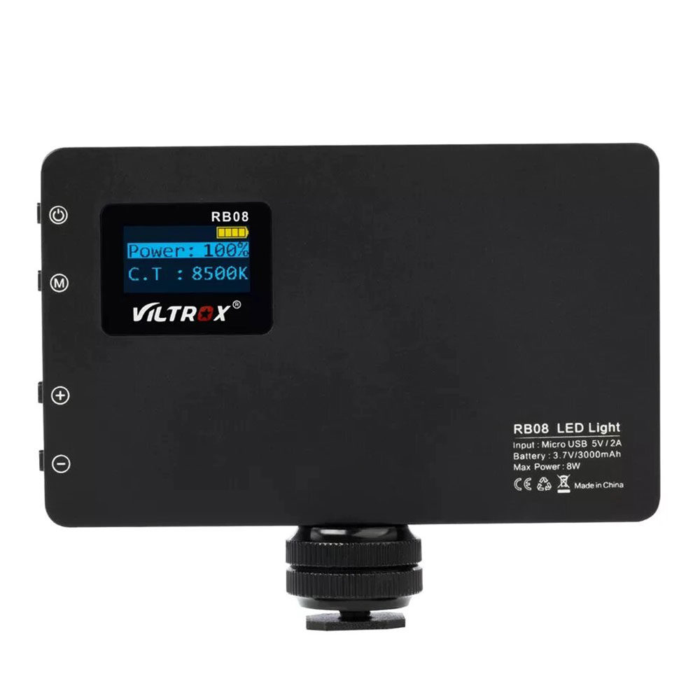 1562766643_329 Musta Viltrox RB08 LED-valo, jossa on pieni näyttö, näyttää tehon 100 %:ssa ja värilämpötilan 8500K. Ohjauspainikkeet ovat vasemmalla, ja kiinnitystarvikkeet on kiinnitetty pohjaan.