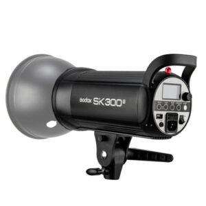 1603176374_380 Mustaa Godox SK300II -studiostroboskooppivalaisinta, jossa on digitaalinen näyttö ja ohjauspainikkeet, näytetään kiinnitettynä kiinnikkeeseen kulmasta, joka paljastaa sekä sen etu- että sivupuolen.