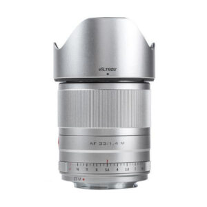 Hopeinen Viltrox AF 33mm f/1.4 -objektiivi Fuji X:lle seisoo pystyssä valkoisella taustalla, ja siinä on tarkennusrengas ja vastavalosuoja.