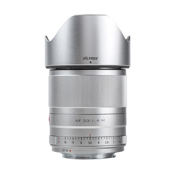 Hopeinen Viltrox AF 33mm f/1.4 -objektiivi Fuji X:lle seisoo pystyssä valkoisella taustalla, ja siinä on tarkennusrengas ja vastavalosuoja.