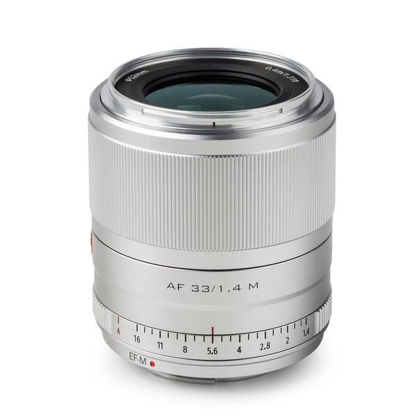 Hopeinen Viltrox AF 33mm f/1.4 -objektiivi, Fuji X -objektiivi seisoo pystyasennossa valkoisella taustalla, ja siinä lukee "AF 33/1.4 M" ja "Viltrox", ja siinä on manuaalitarkennuksen ja aukon säätörenkaat.