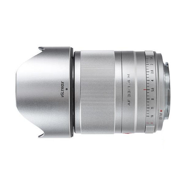 Hopeinen Viltrox AF 33mm f/1.4 -objektiivi Fuji X:lle, jossa on harjattu tarkennusrengas, aukkomerkinnät ja kiinnitetty huppu, kuvattuna sivulta valkoisella taustalla.