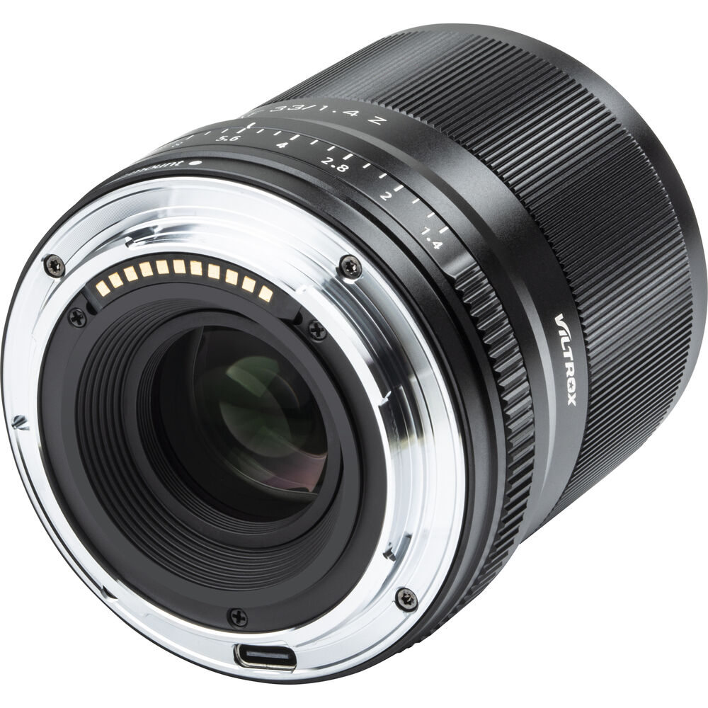 Lähikuva Viltrox AF 33mm f/1.4 -objektiivi, Nikon Z -objektiivista, jossa korostuvat sen metallinen kiinnitys, elektroniset koskettimet, objektiivilasi ja tarkennusetäisyysmerkinnät tynnyrissä.