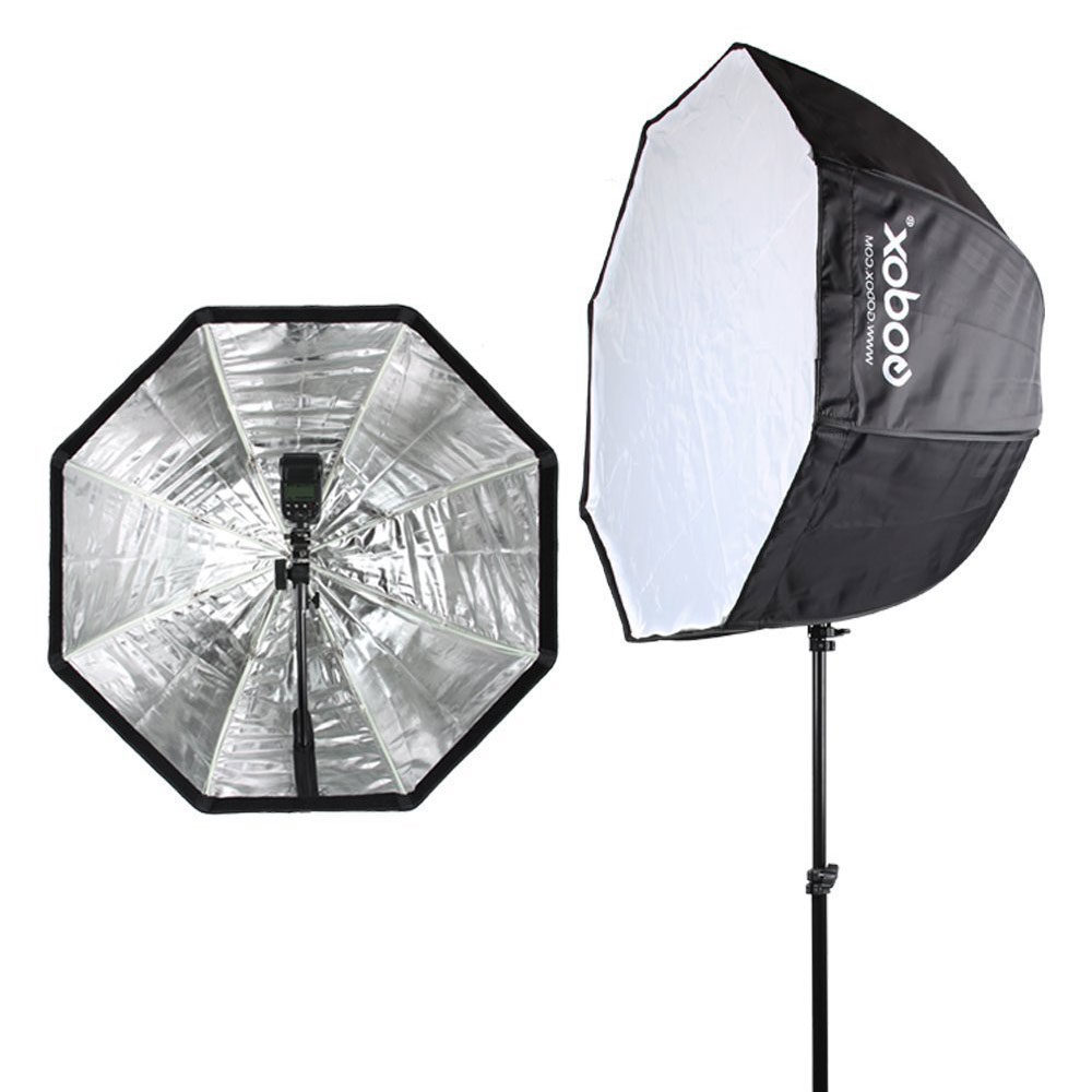 1640781098_819 Kaksi Godox SB-UBW80 Octa Umbrella Softboxia (80cm) mustalla jalustalla - yksi eteenpäin suunnattu ja hopeanvärinen heijastava sisäpuoli, toinen sivuttain, jossa on valkoinen diffuusiopaneeli ja Godox-brändi sivullaan.