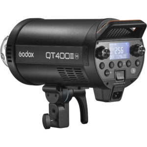 1643029787_938 Musta Godox QT400IIIM-stroboskooppivalaisin, jossa on digitaalinen näyttö, ohjauspainikkeet ja kiinnitysteline, pienestä kulmasta katsottuna.