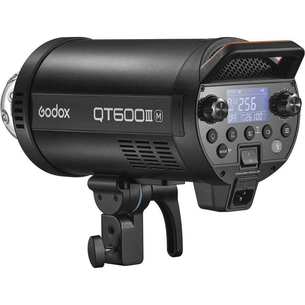 1643029901_163 Musta Godox QT600IIIM -studiostroboskooppivalaisin, jossa on ohjauspainikkeet, digitaalinen näyttö ja kiinnitysteline, näkyy sivulta valkoista taustaa vasten.